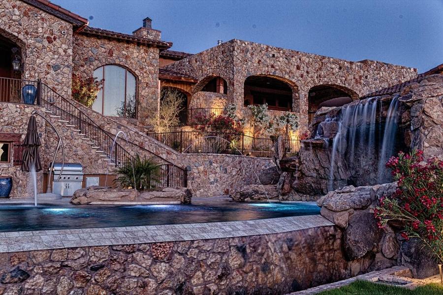 Resort style pool with lit waterfall at dusk