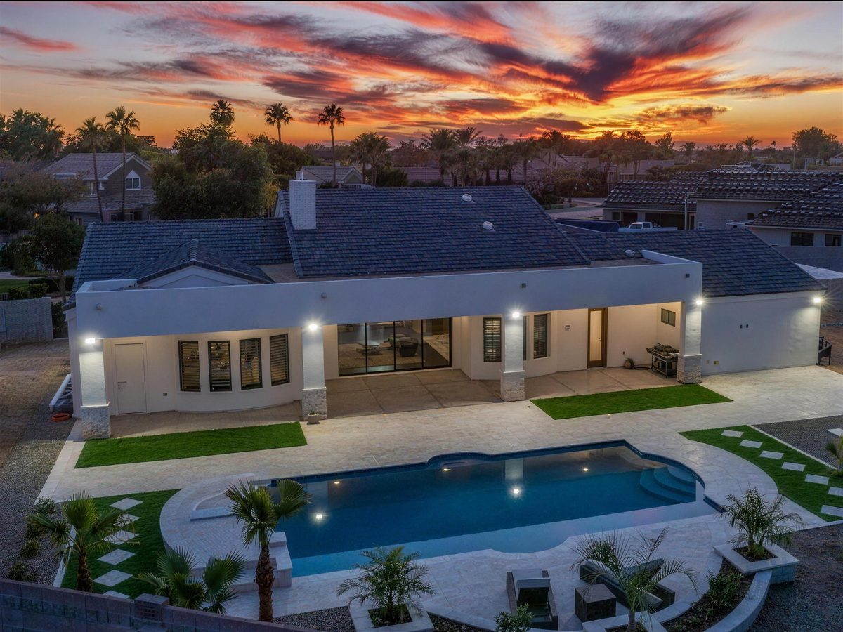 Aerial of a lit freeform pool and home at sunset