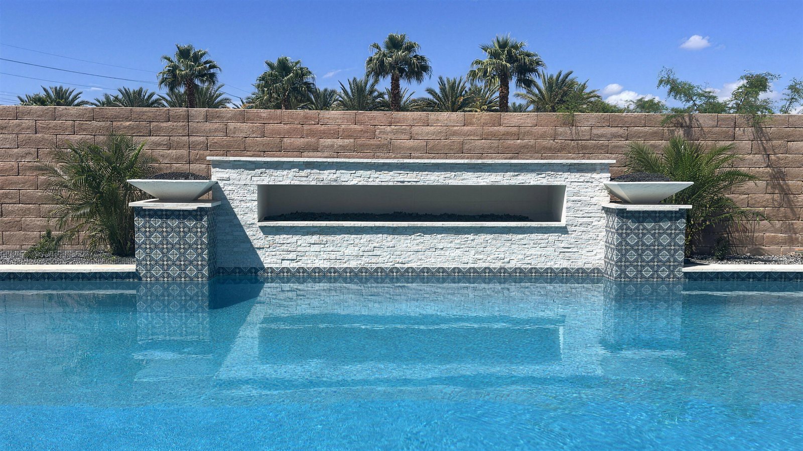 The same view built: fire wall with sheer descent, fire bowls, patterned tile and raised spa